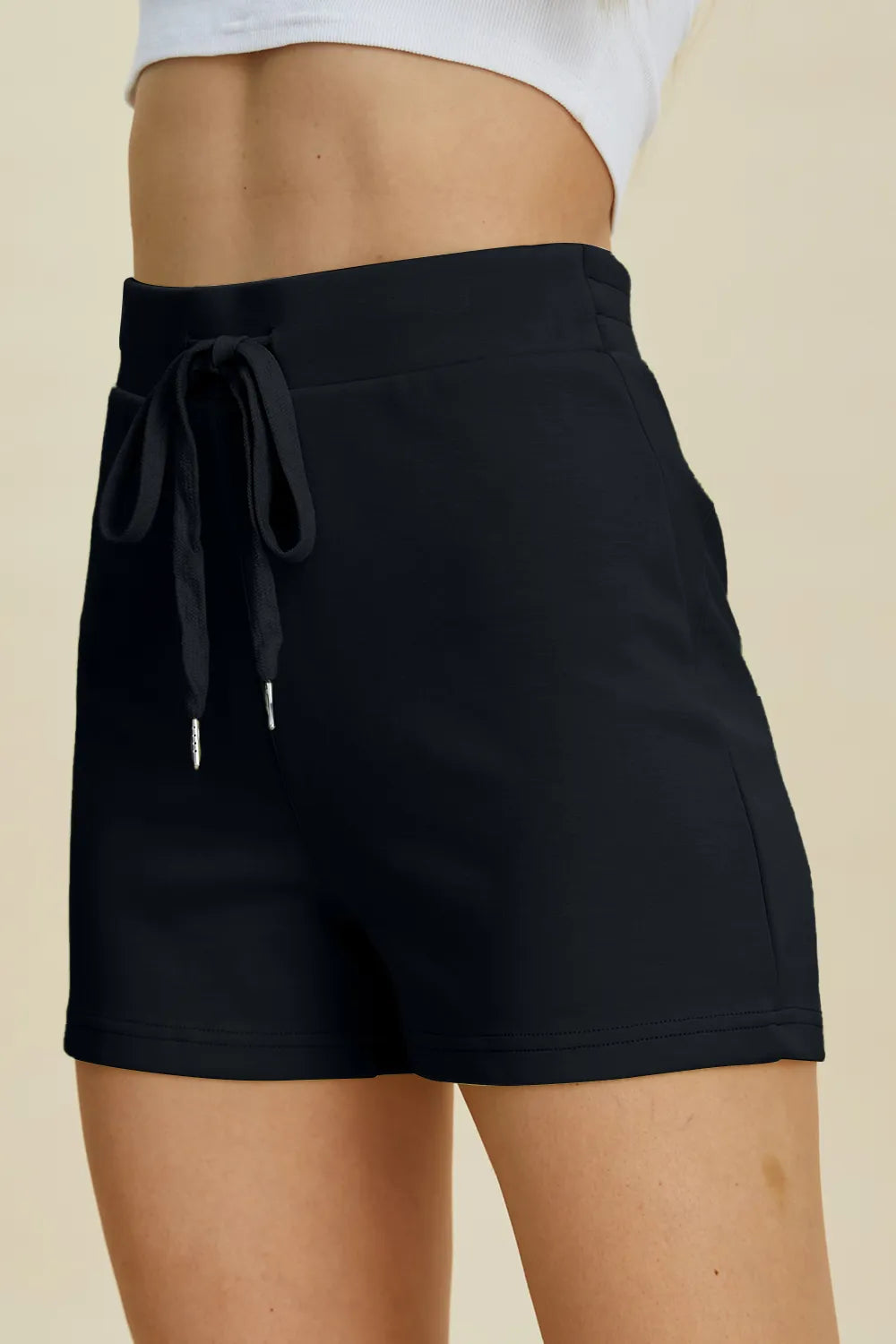Black shorts with a drawstring on a beige background