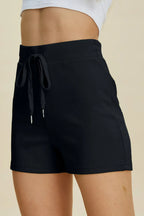 Black shorts with a drawstring on a beige background
