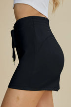 Black shorts worn by a person on a beige background