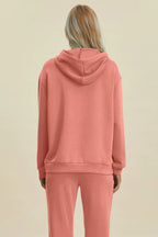 Person wearing a pink hoodie and pants on a beige background