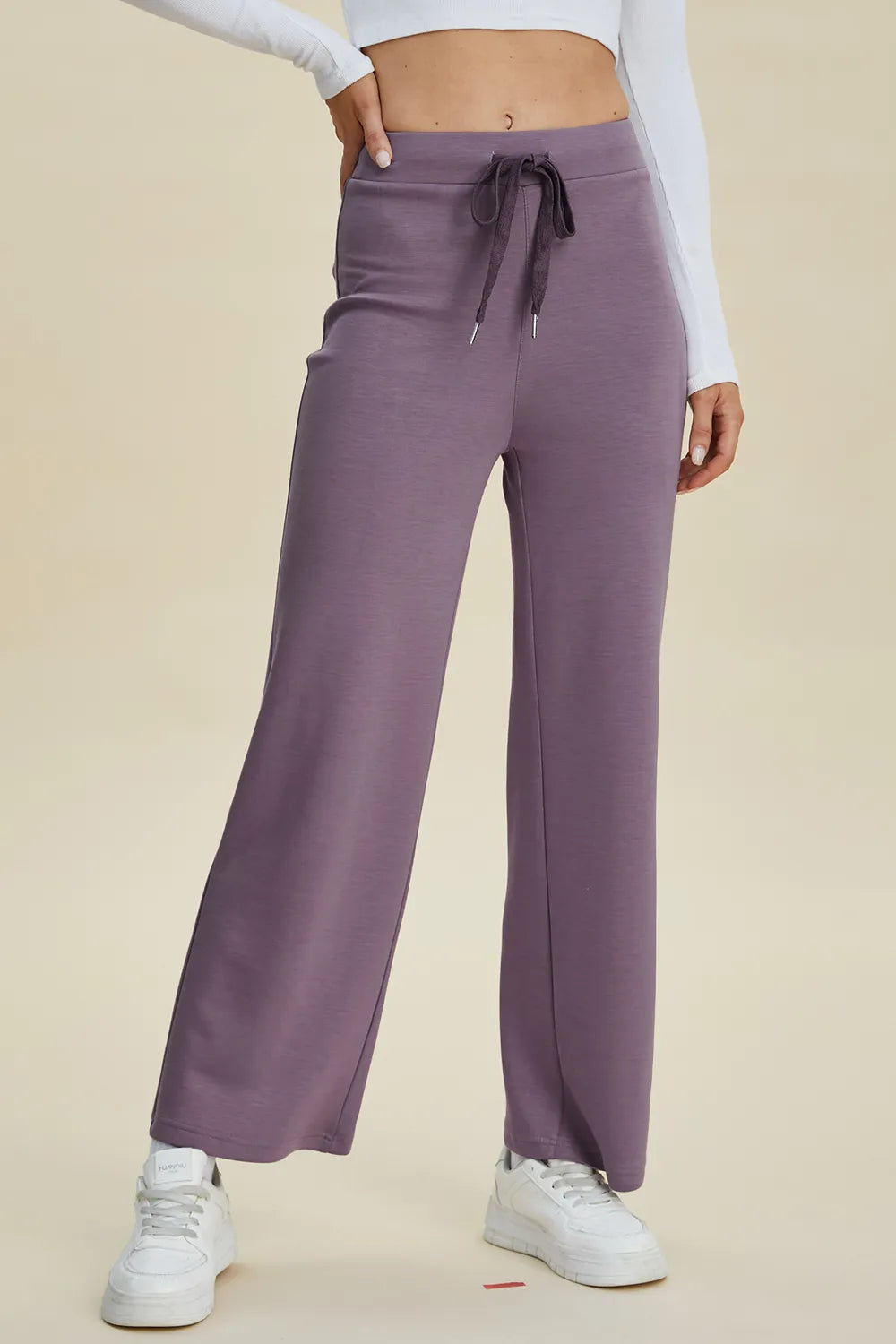Purple sweatpants worn by a person on a beige background