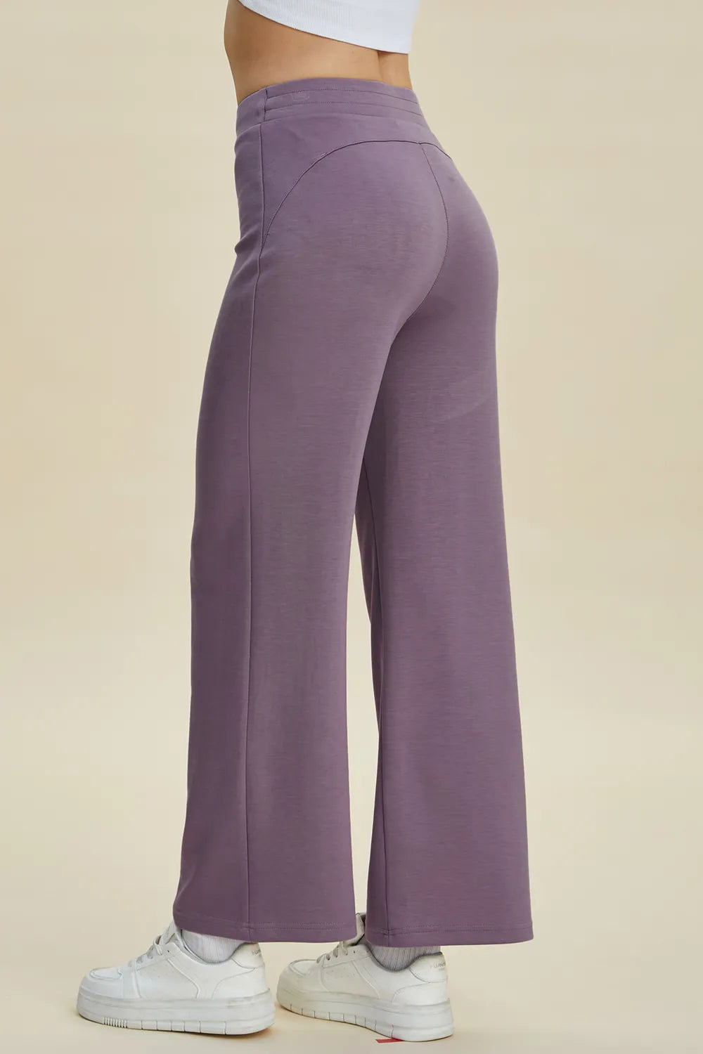 Purple pants worn by a person on a beige background