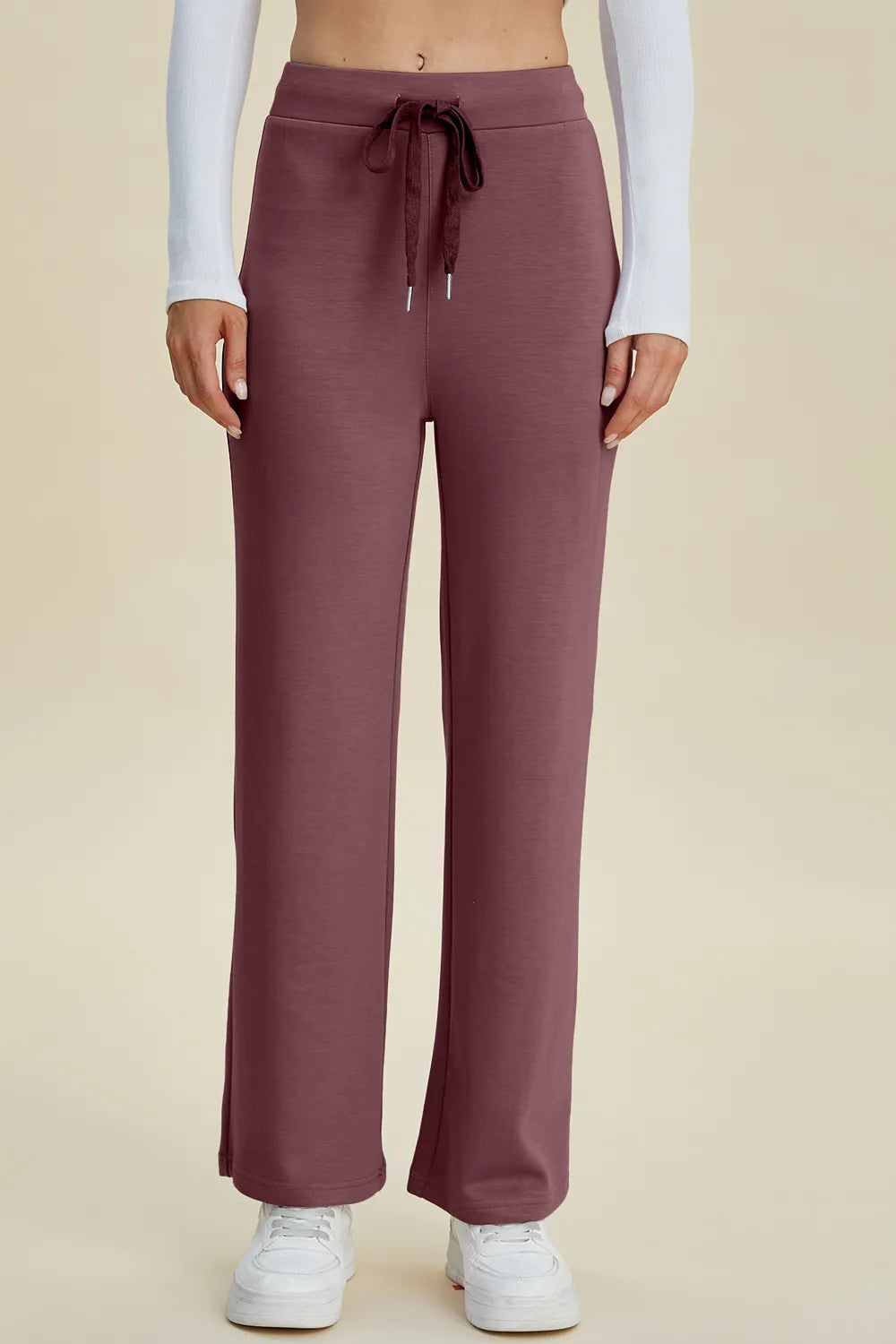 Mauve sweatpants worn by a person on a beige background