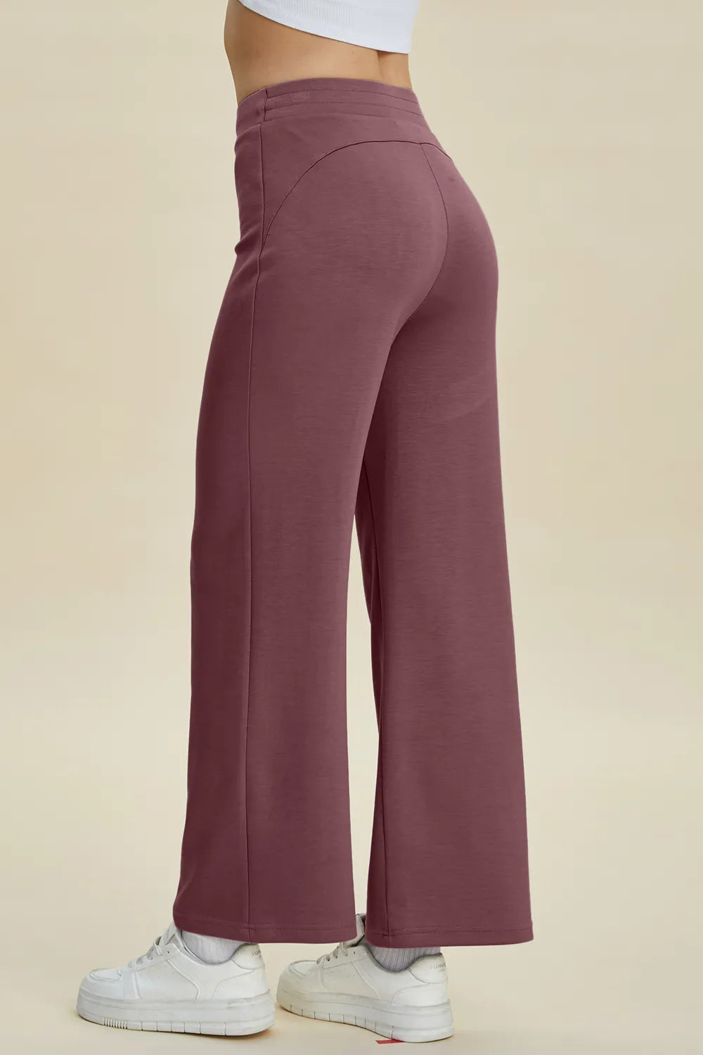 Mauve wide-leg pants worn by a person on a beige background