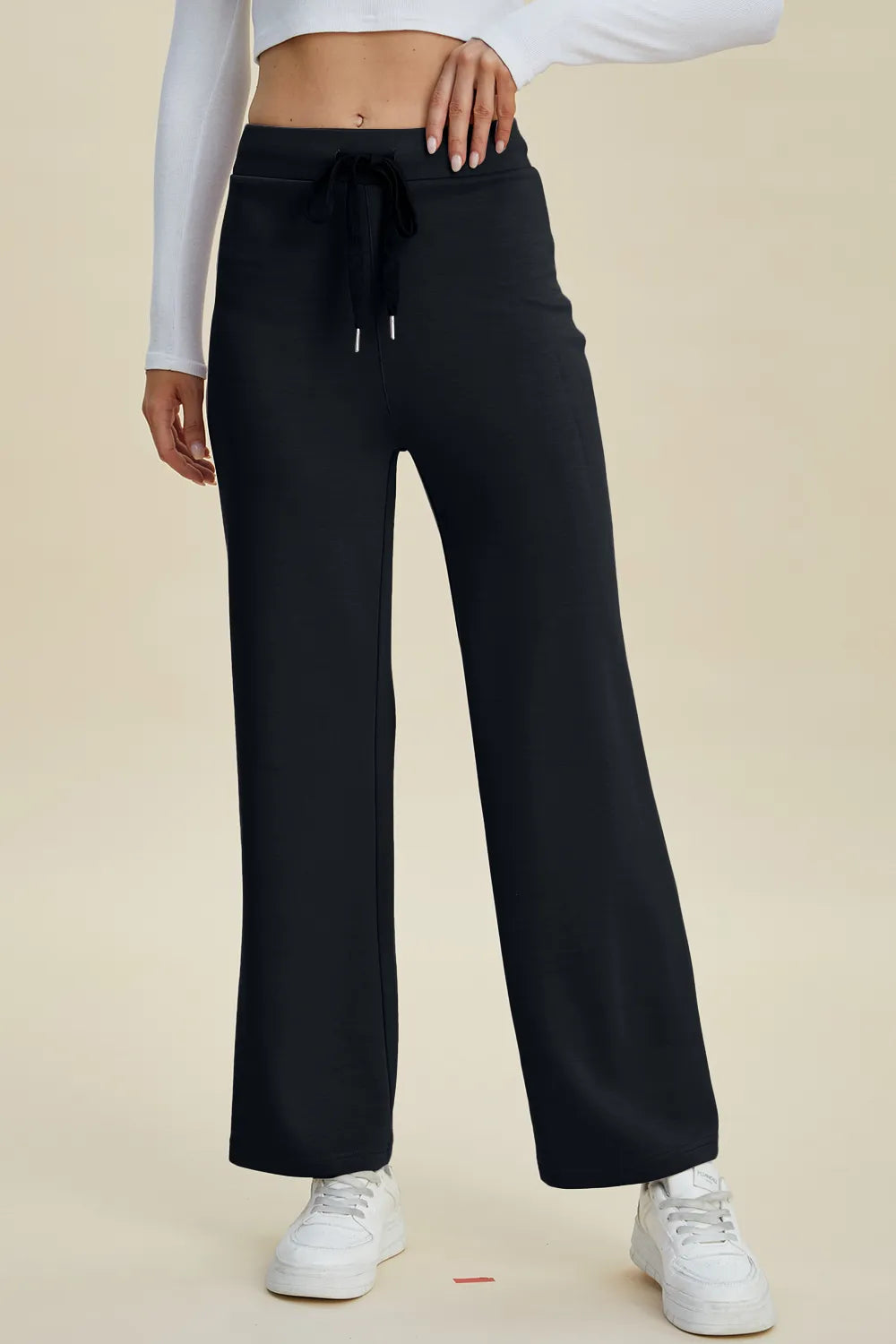Black wide-leg pants worn by a person on a beige background