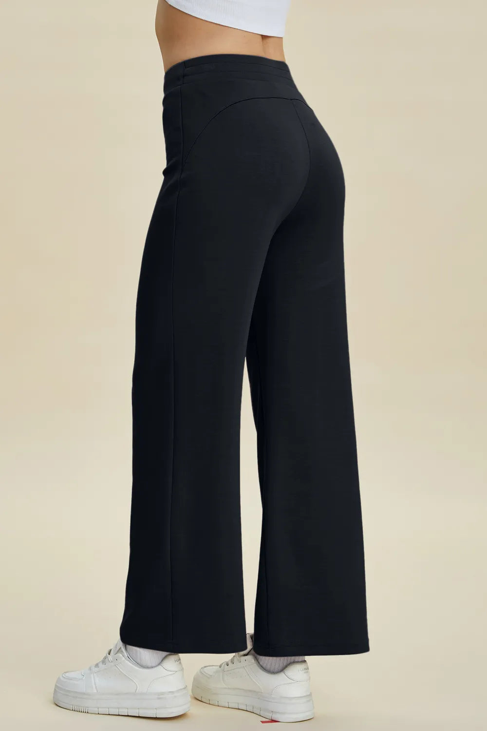 Black wide-leg pants worn by a person on a beige background