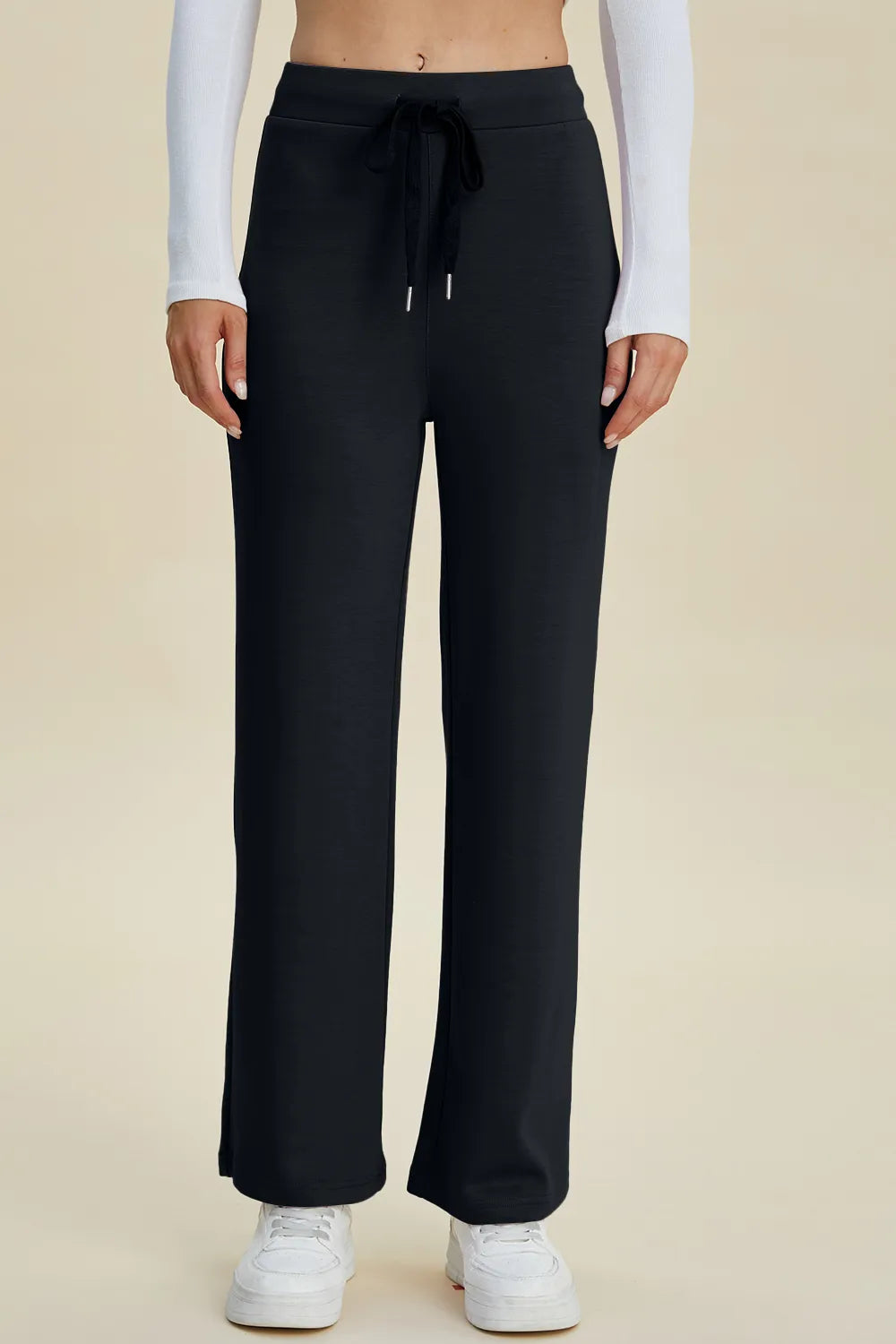 Black wide-leg pants worn by a person on a beige background