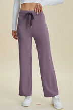 Purple sweatpants worn by a person on a beige background