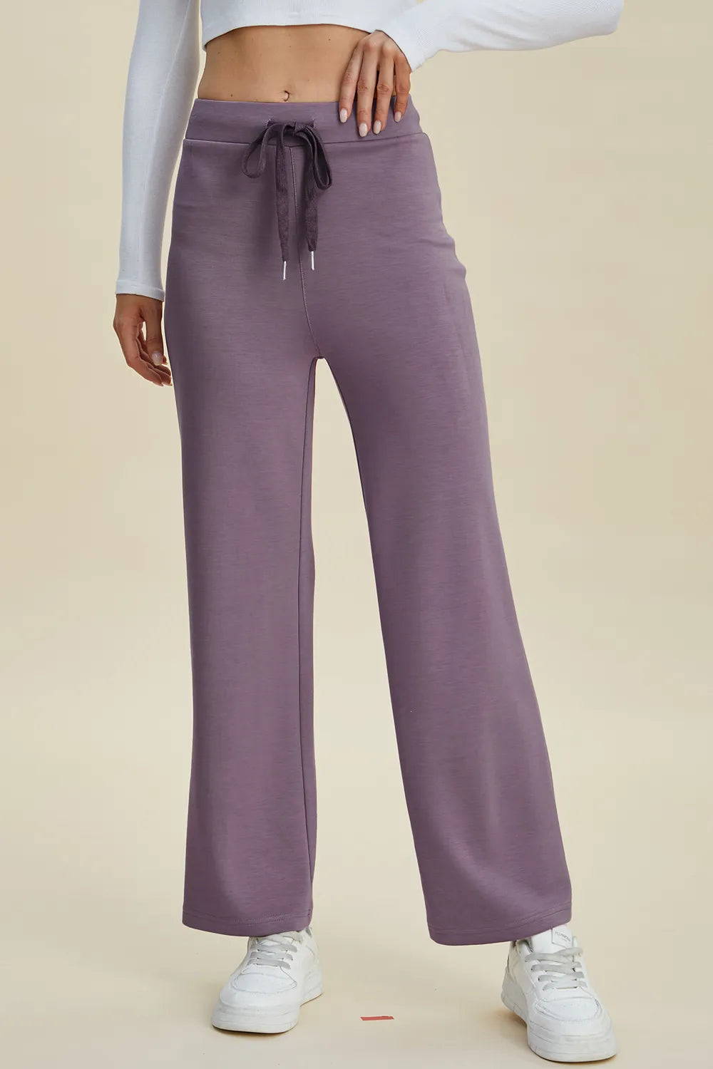 Purple sweatpants worn by a person on a beige background
