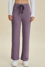 Person wearing purple sweatpants with a drawstring on a beige background