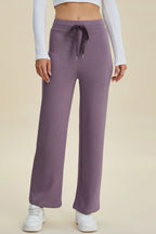 Purple sweatpants worn by a person on a beige background