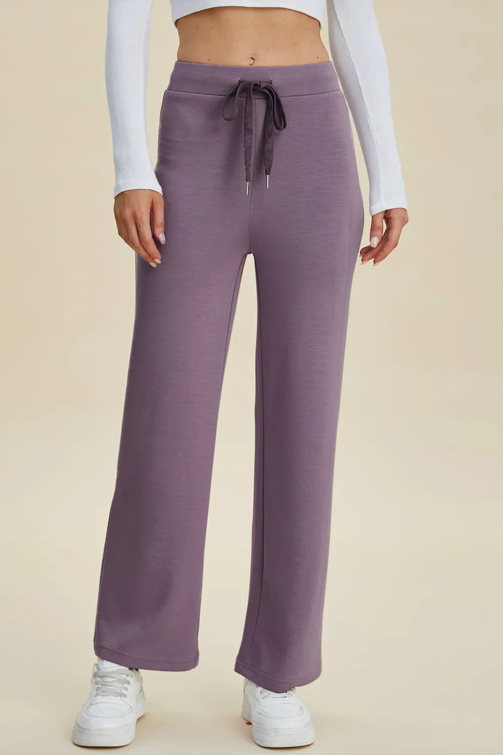 Purple sweatpants worn by a person on a beige background
