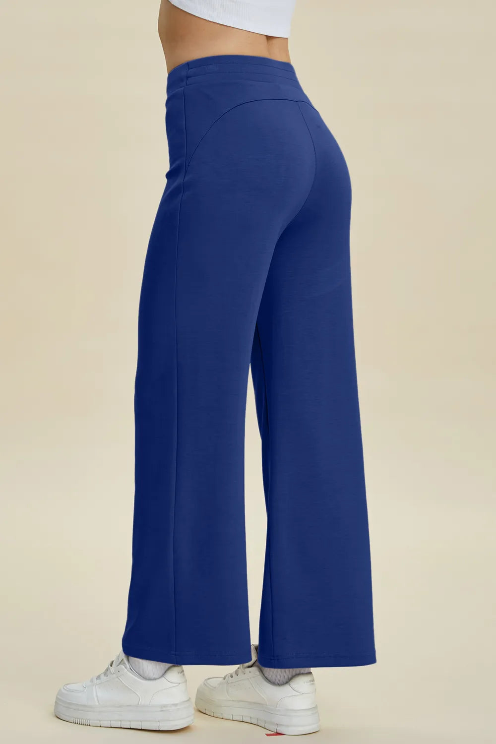 Blue wide-leg pants worn by a person on a beige background
