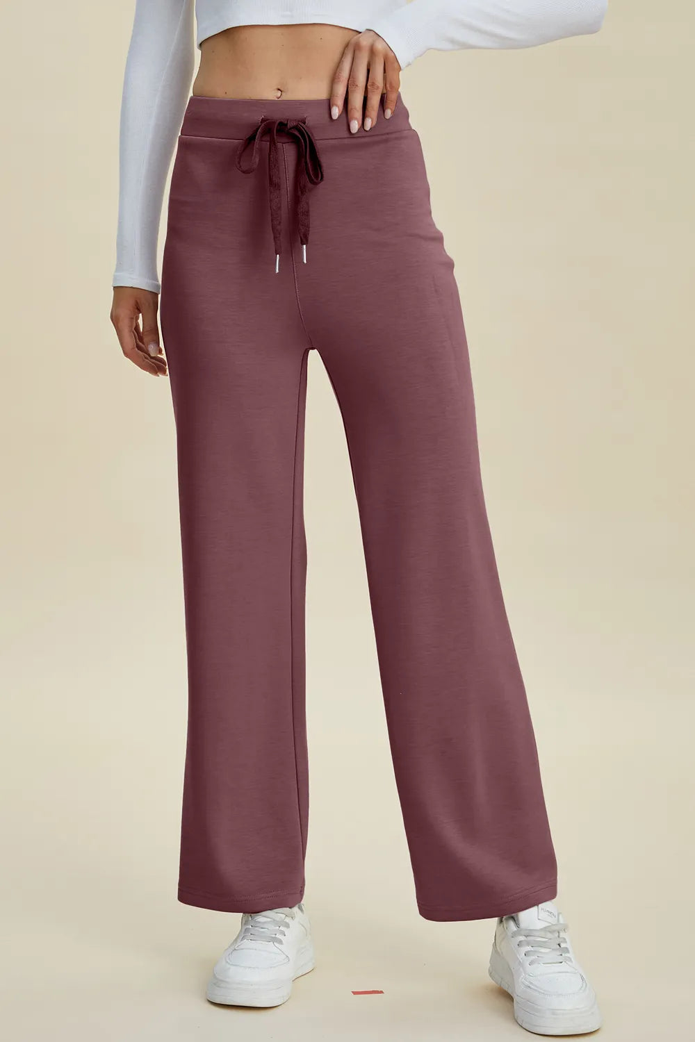 Mauve sweatpants worn by a person on a beige background
