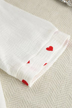 White fabric with red heart patterns on a textured beige surface