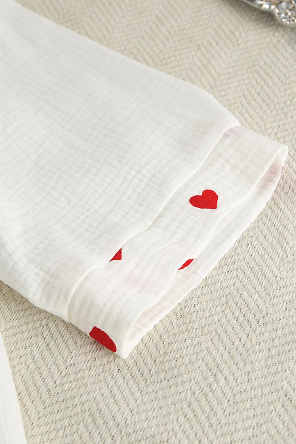 White fabric with red heart patterns on a textured beige surface