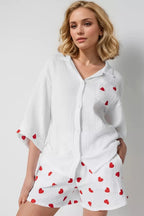 Woman wearing a white outfit with red heart patterns on a plain background