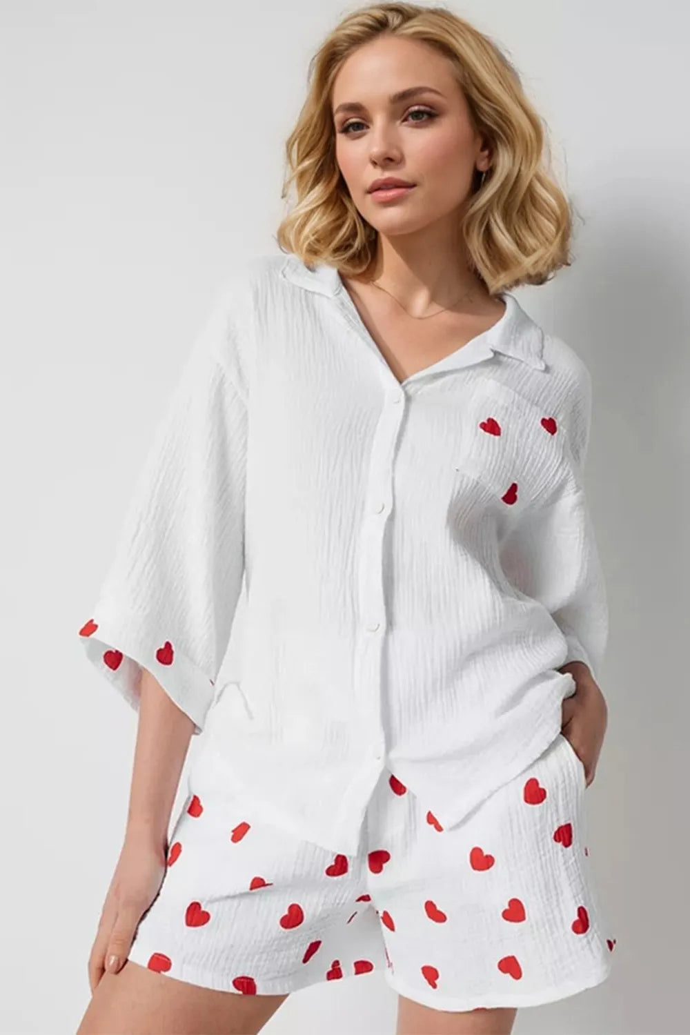Woman wearing a white outfit with red heart patterns on a plain background