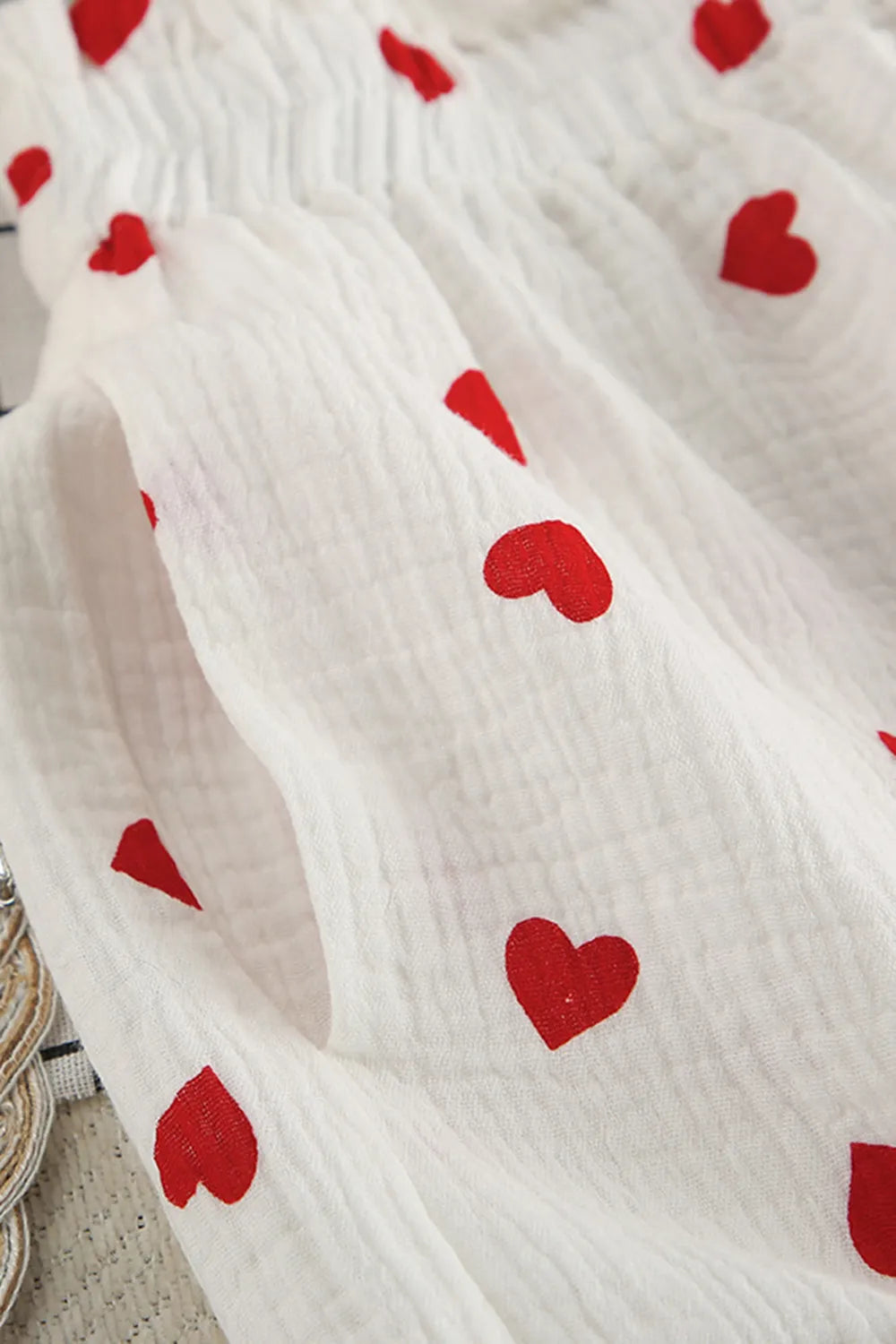 White fabric with red heart patterns on a neutral background