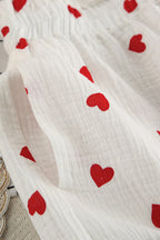 White fabric with red heart patterns on a neutral background