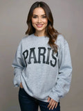 Woman wearing a gray sweatshirt with 'PARIS' printed on it against a plain background
