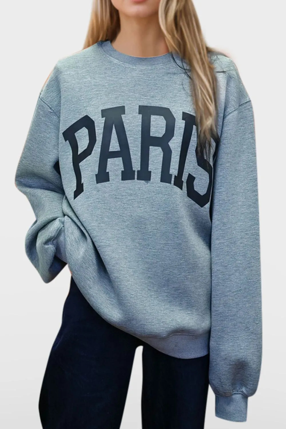 Person wearing a blue sweatshirt with 'PARIS' printed on it against a white background