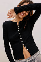 Woman wearing a black cardigan with pearl buttons on a plain background