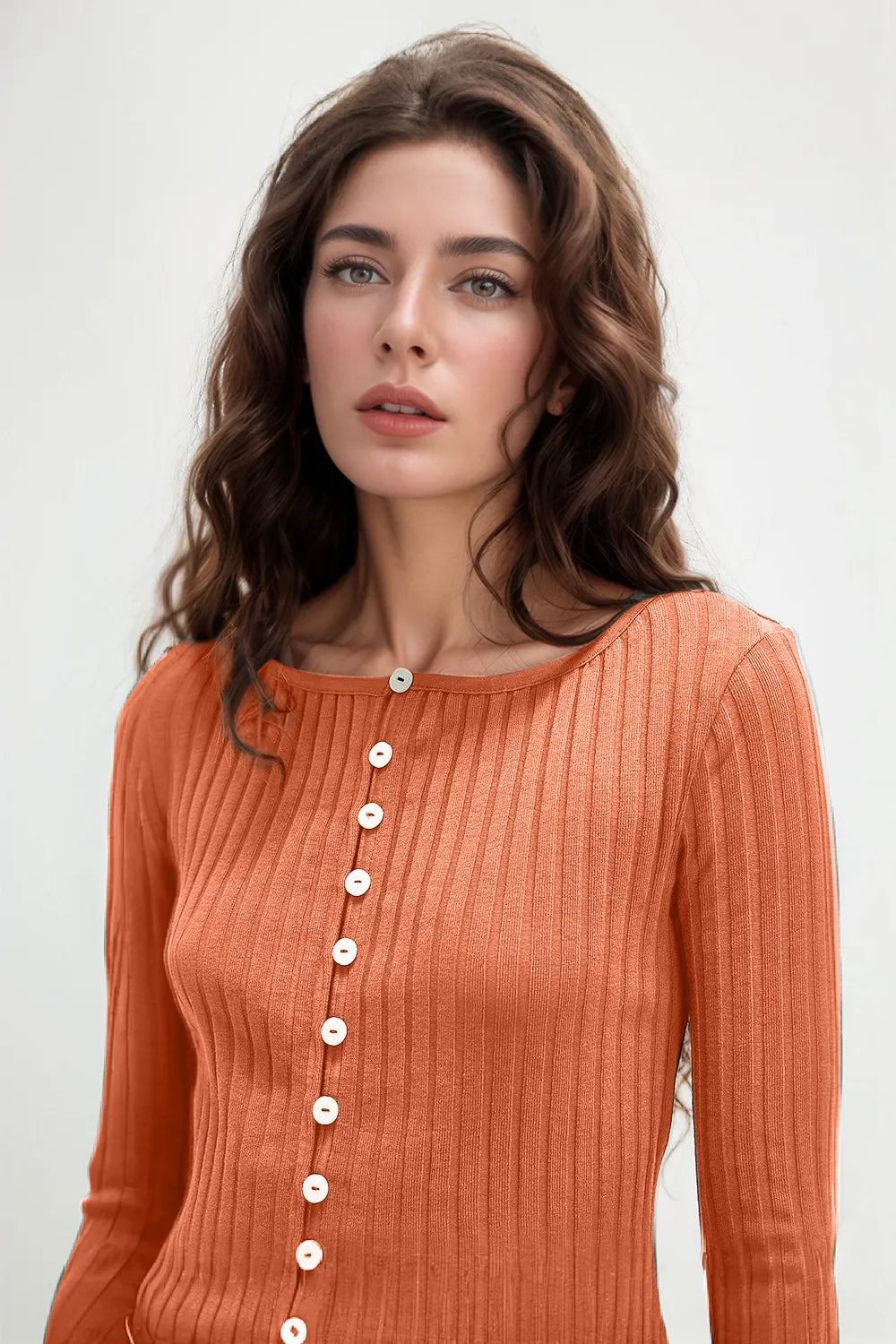 Woman wearing an orange ribbed sweater with buttons on a white background