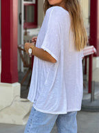 Person wearing a white oversized t-shirt and blue jeans in an outdoor setting.