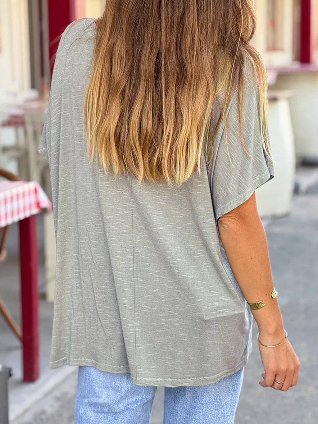 Person wearing a gray oversized t-shirt and light blue jeans on a street.