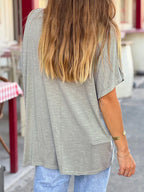 Person wearing a gray oversized t-shirt and light blue jeans on a street.