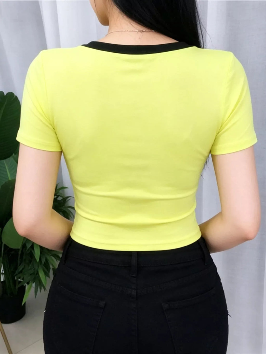 Person wearing a bright yellow top with black trim against a neutral background
