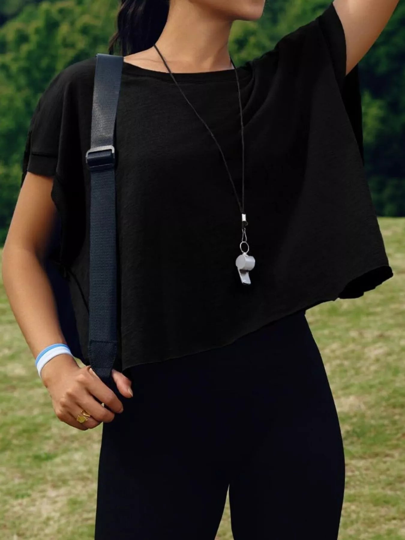 Person wearing a black shirt and carrying a black bag outdoors