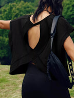 Person wearing a black outfit with an open back, carrying a black bag outdoors.