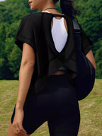 Person wearing a black outfit with a white back design, standing outdoors.