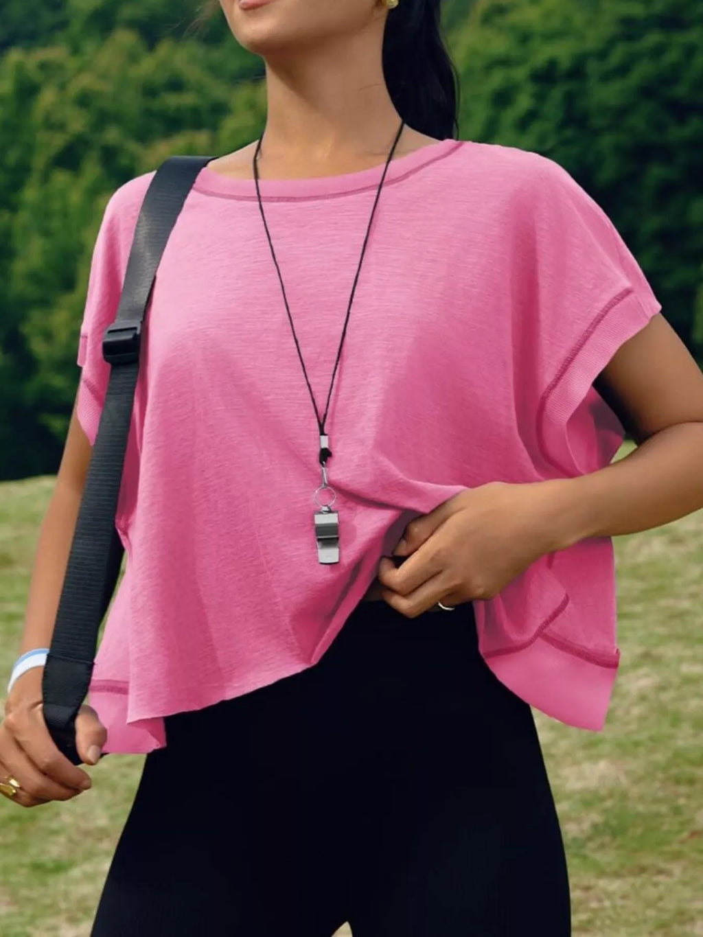 Person wearing a pink top and black pants outdoors