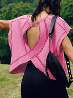 Person wearing a pink sleeveless top with a black bag over their shoulder outdoors.