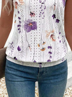 Person wearing a white sleeveless top with floral patterns and blue jeans.