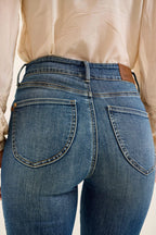 Close-up of blue jeans with a beige shirt in the background