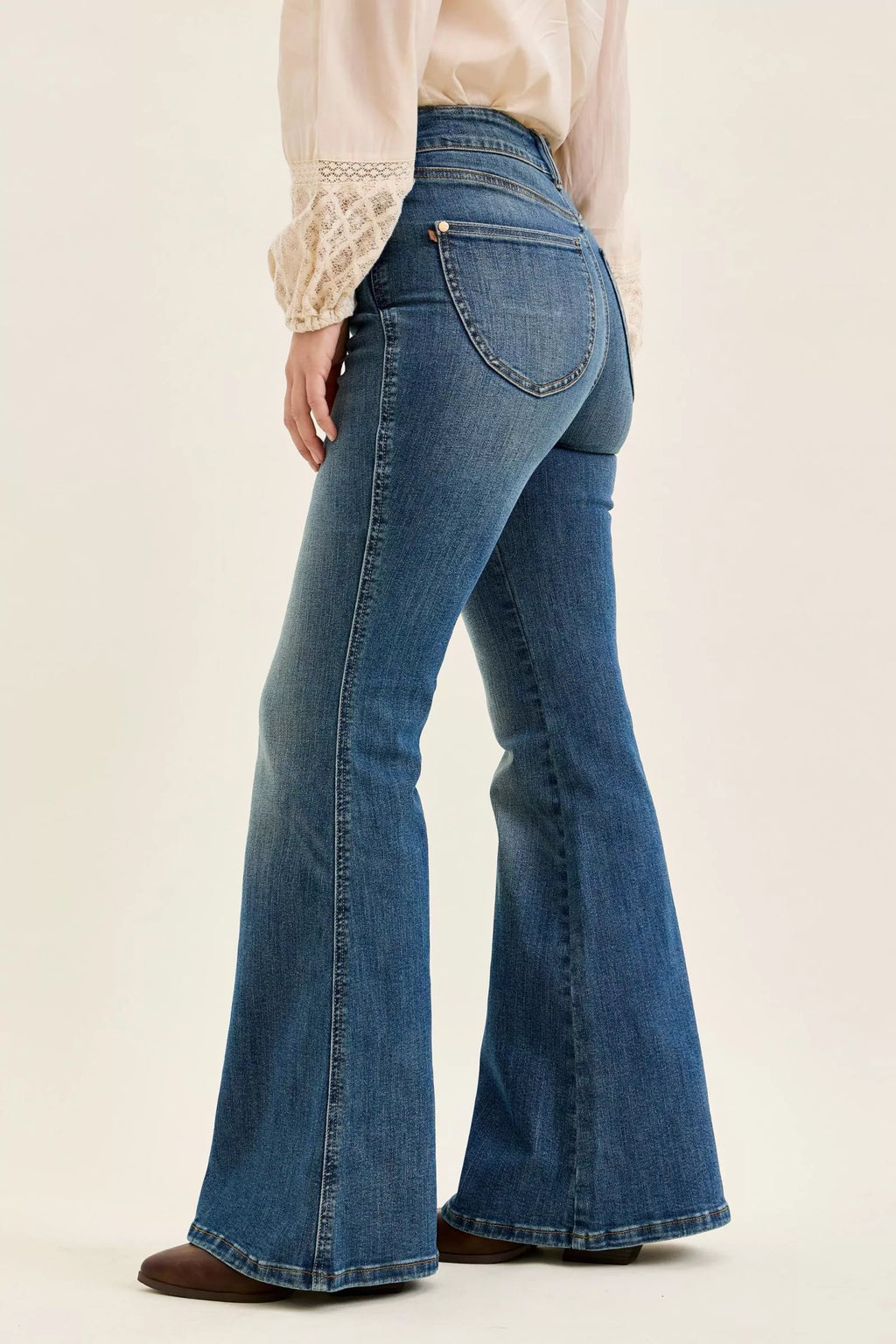 Blue flared jeans worn by a person on a beige background
