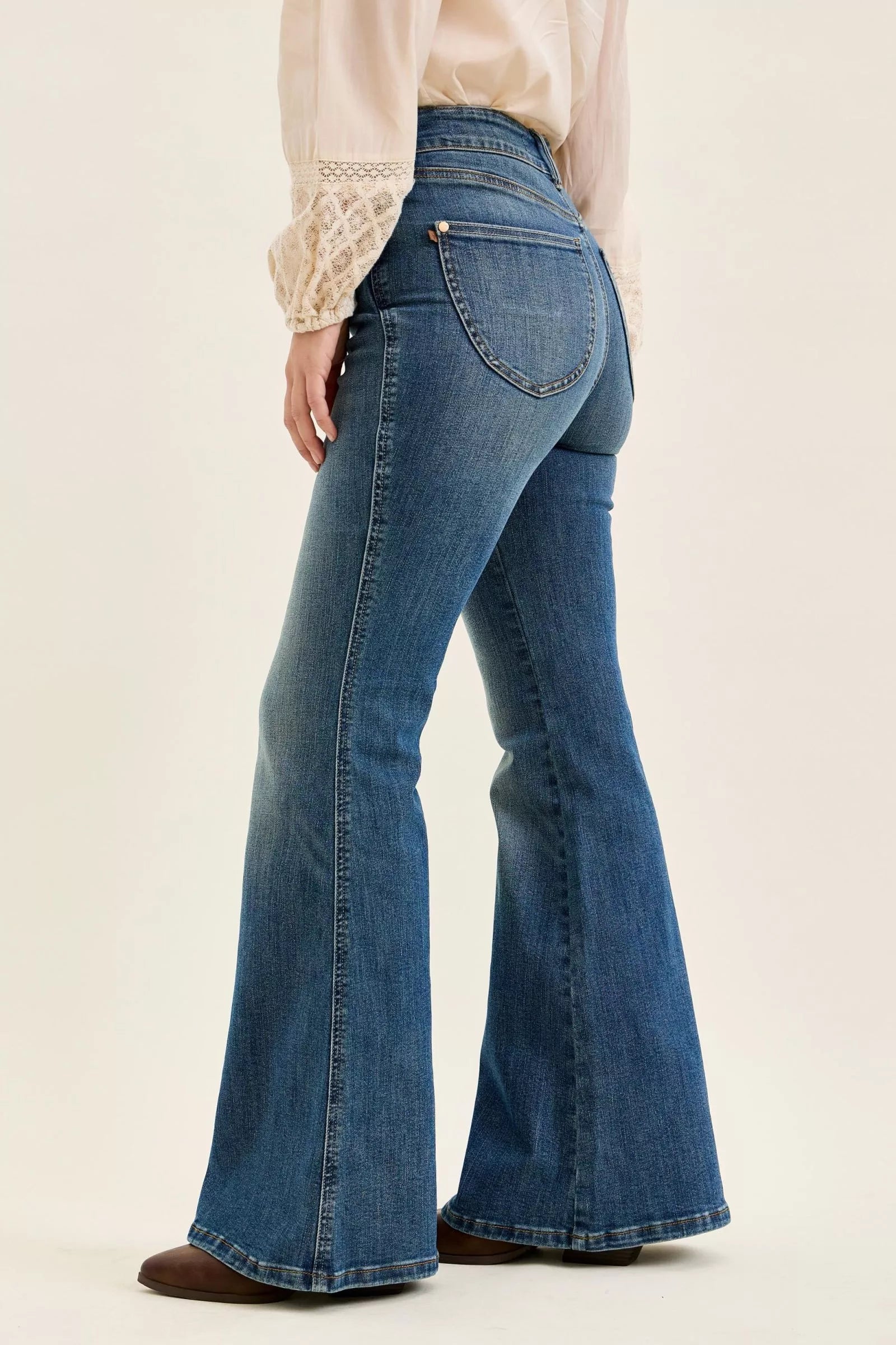 Blue flared jeans worn by a person on a beige background