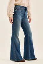 Blue flared jeans worn by a person on a plain background