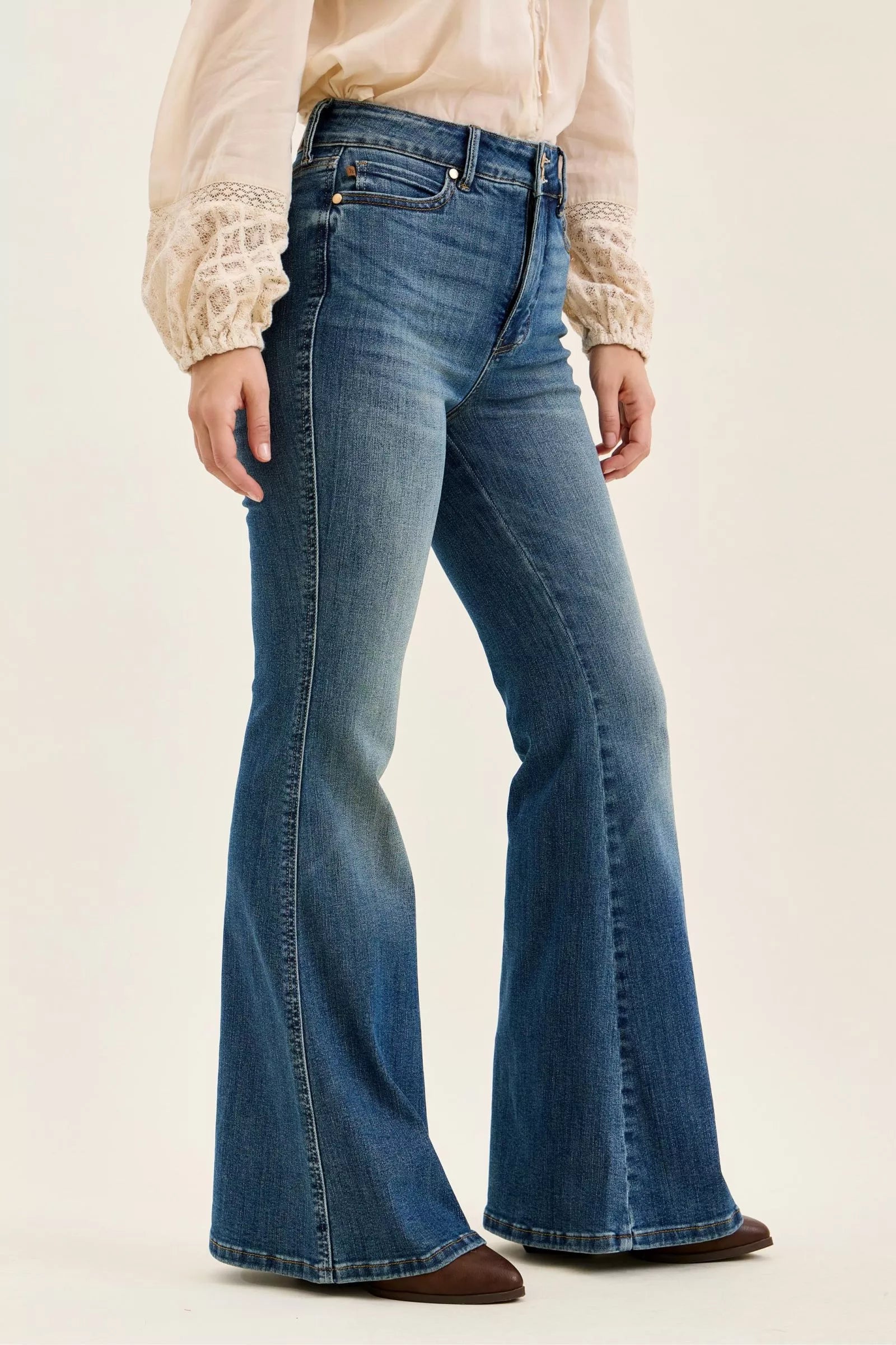 Blue flared jeans worn by a person on a plain background