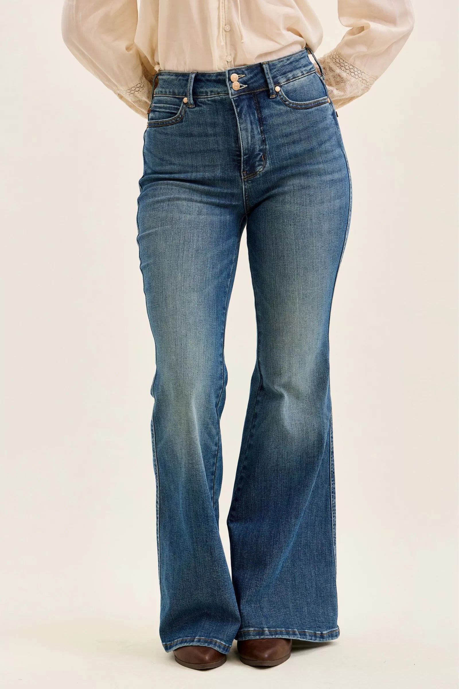 Flared jeans worn by a person on a beige background