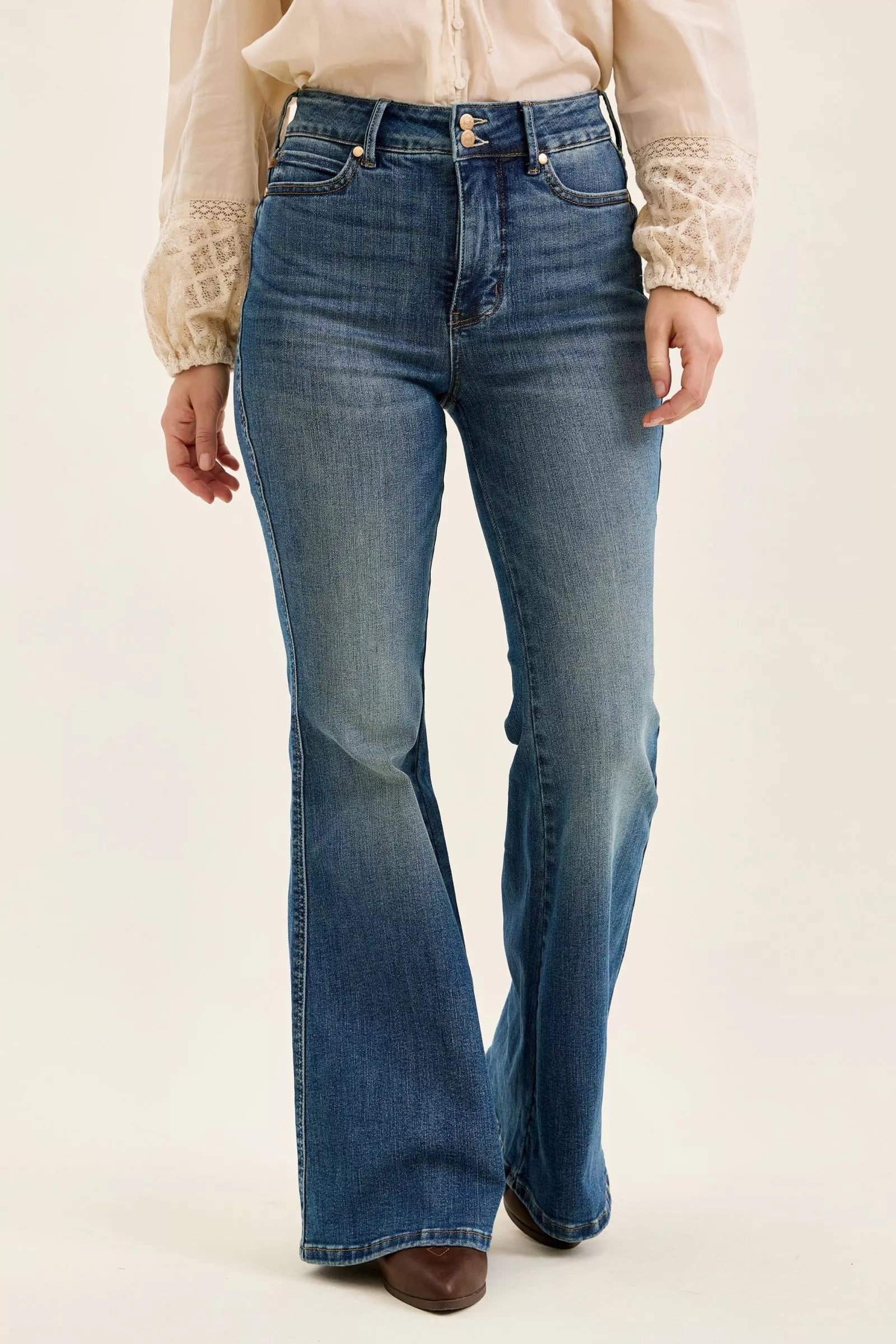 Person wearing blue flared jeans on a plain background