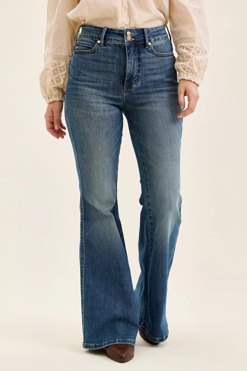 Person wearing blue flared jeans on a plain background