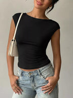 Person wearing a black top and light blue jeans with a beige handbag on a neutral background
