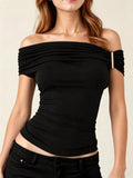 Black off-shoulder top worn by a person on a beige background