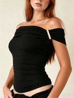 Woman wearing a black off-shoulder top against a plain background