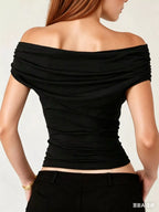 Black off-shoulder top worn by a person on a plain background